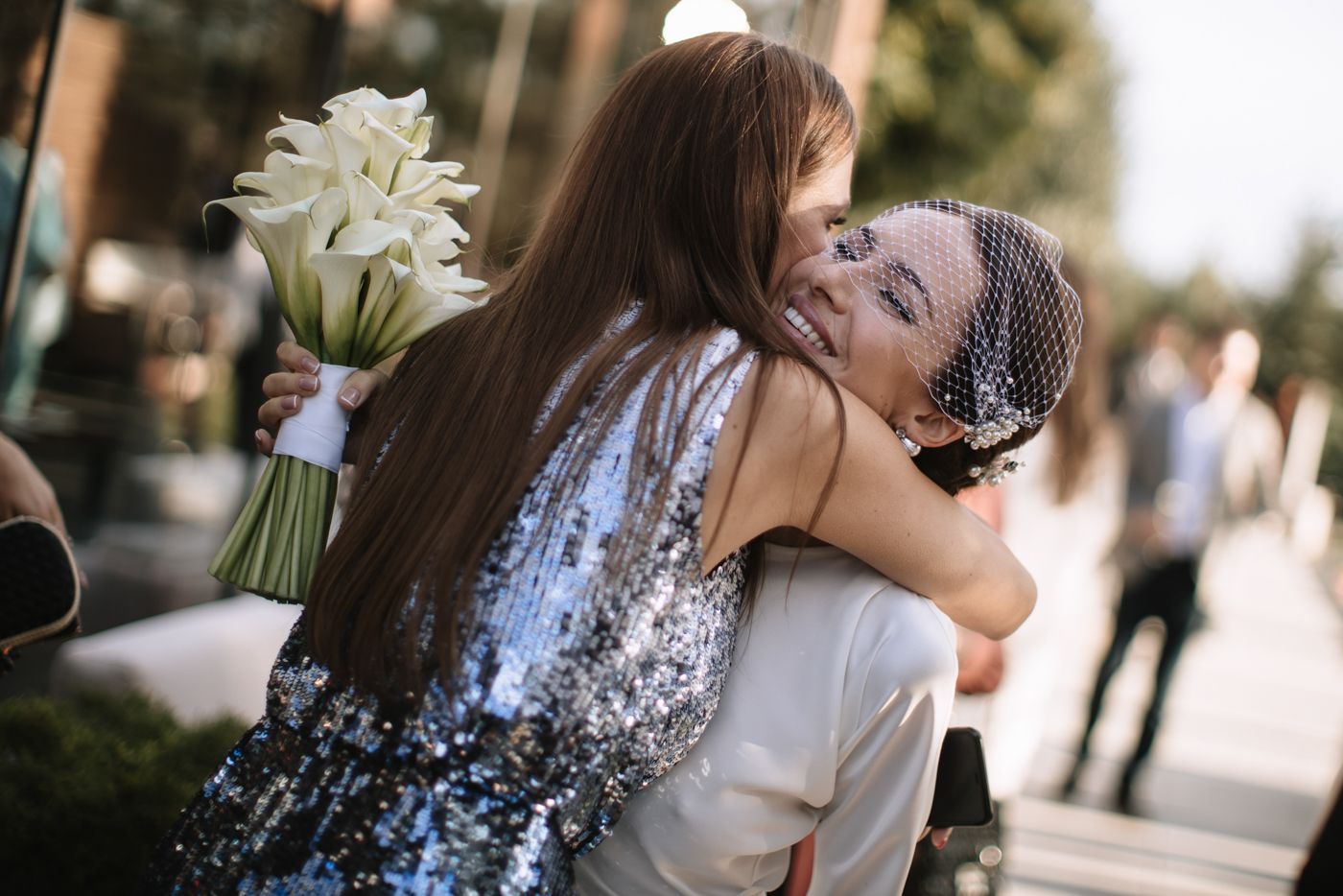 Emotional wedding moment captured with white lily bouquet and sparkly dress.