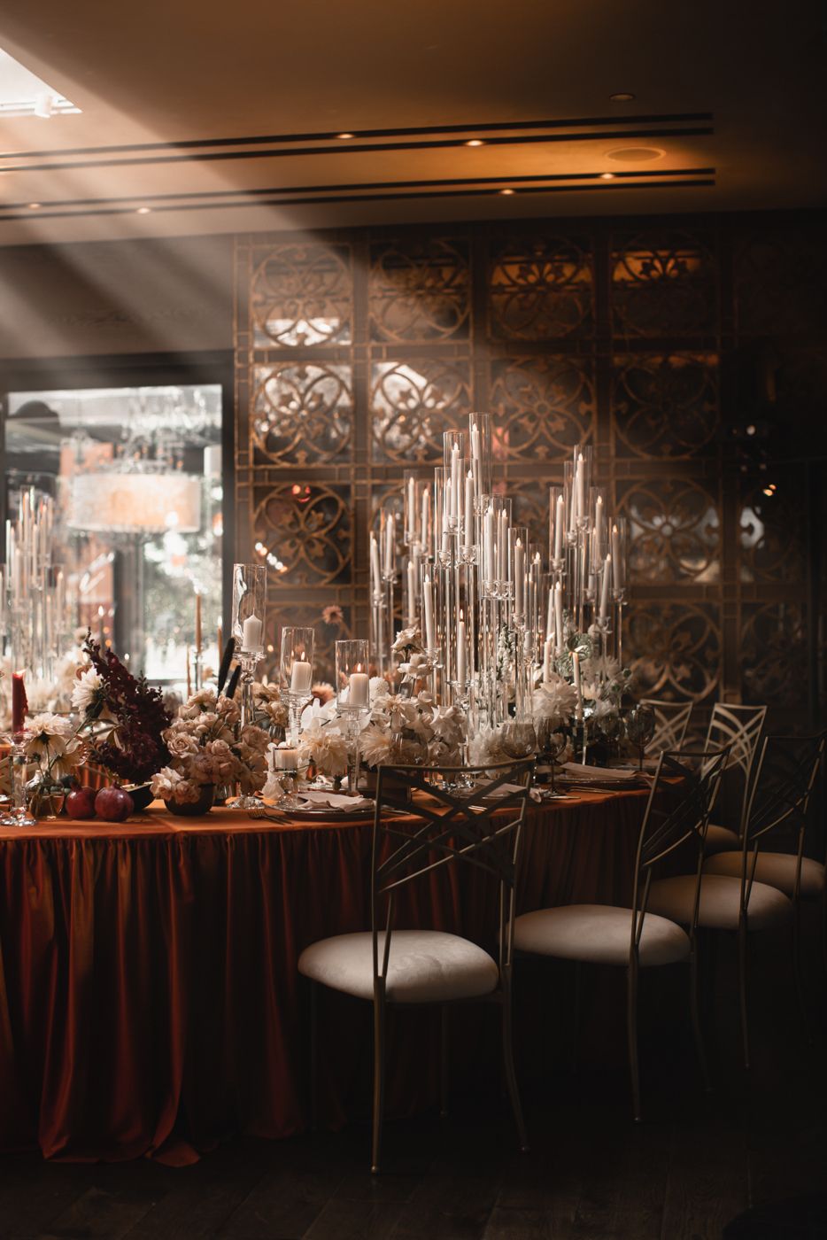 Elegant wedding reception table setup with tall candles and moody lighting.