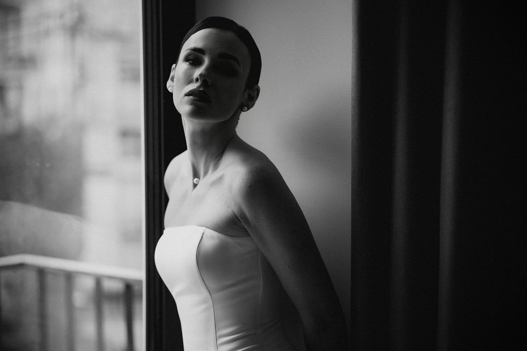 Dramatic black and white portraits capture a bride's silhouette against window light and dark curtains.