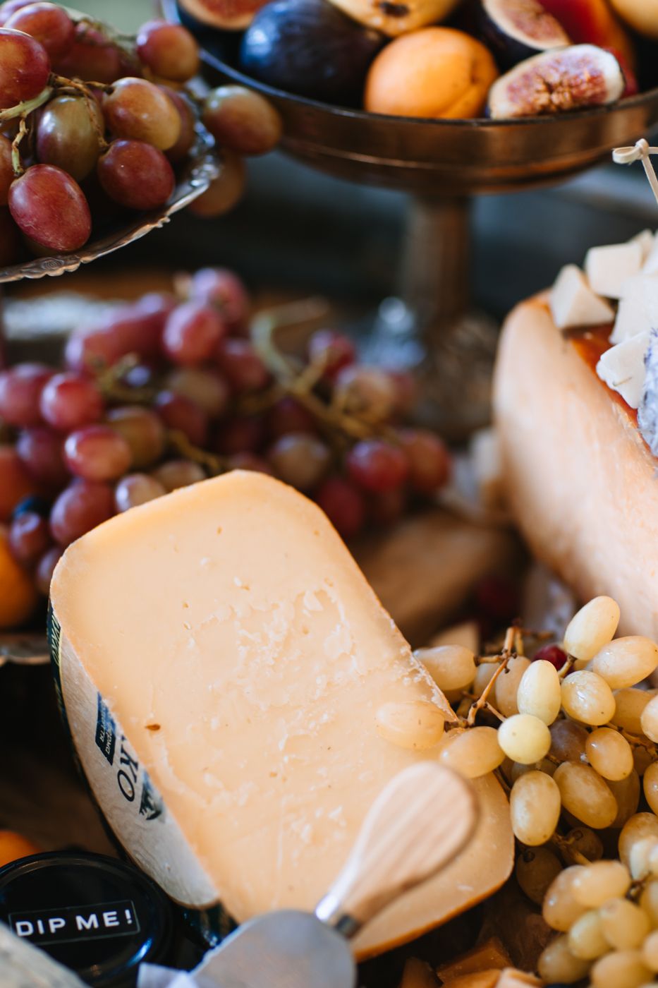 Close-up view of creamy white cheese and fresh grapes arranged on a rustic wooden serving board.