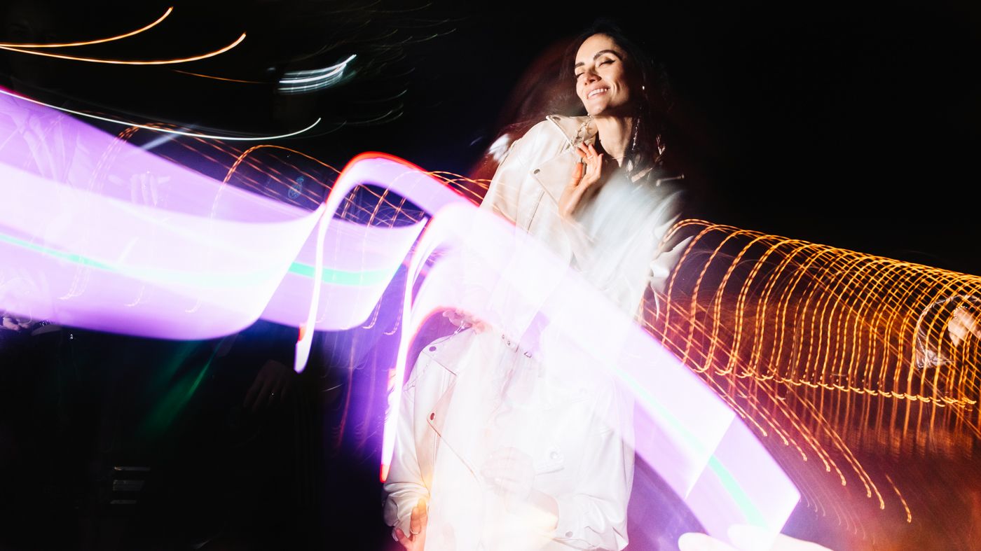 Long exposure photograph shows vibrant light trails creating colorful streaks against a dark background.
