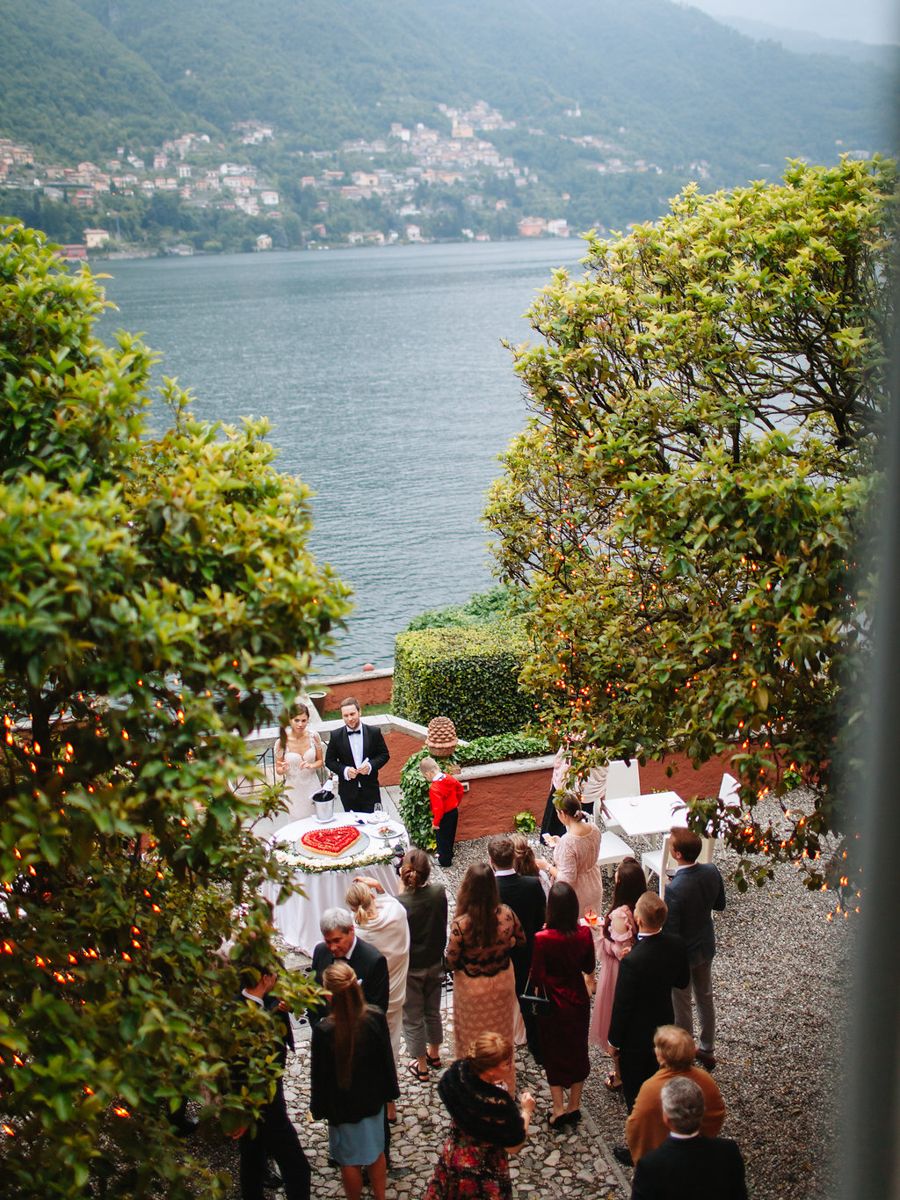 A scenic outdoor wedding ceremony overlooking Lake Como in Italy with mountains and greenery in the background.