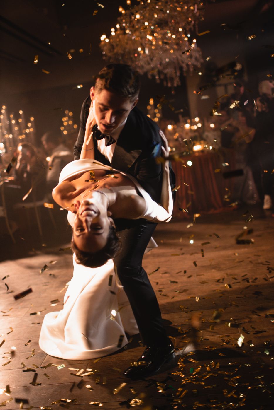 Dancing couple spins on dance floor with confetti falling around them.