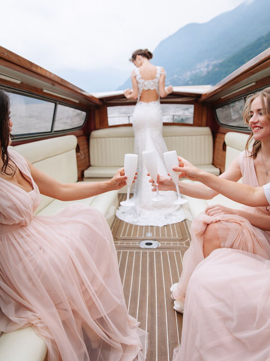 Elegant pink tulle wedding dress being prepared on a yacht with mountains in the background.