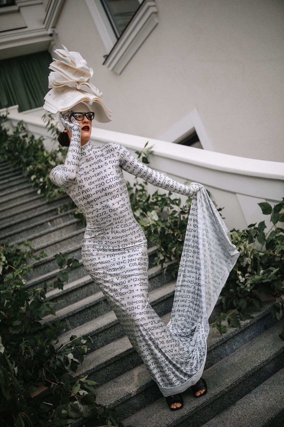 A person wearing a text-patterned dress and hat poses dramatically on outdoor steps in a series of artistic shots.