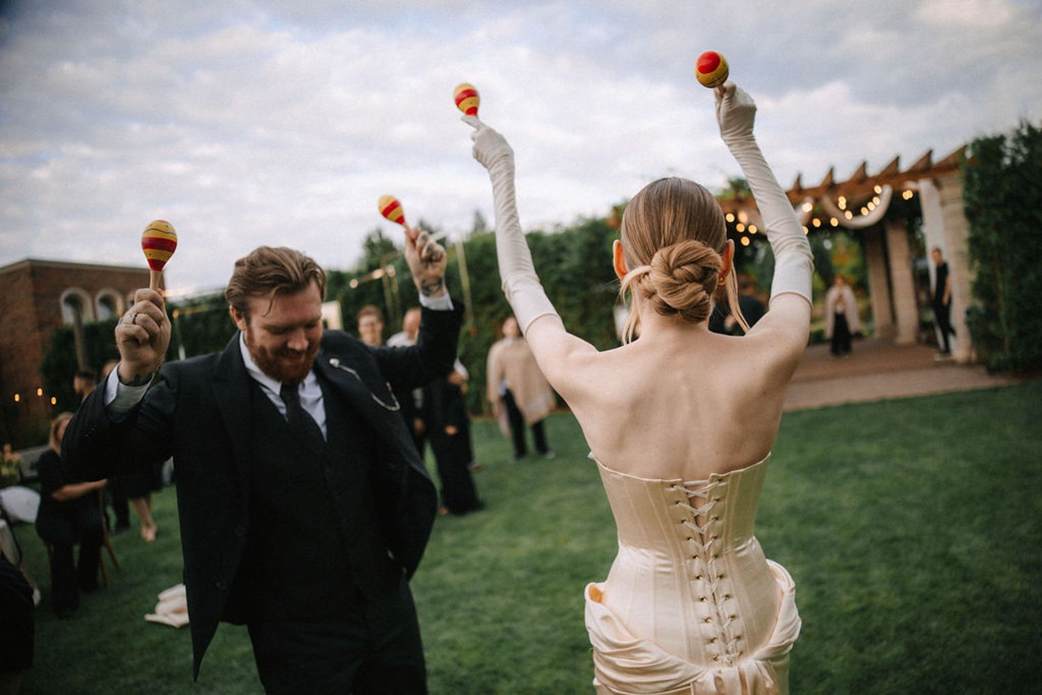 Wedding party celebrates outdoors with raised champagne glasses at sunset during a joyful toast ceremony.