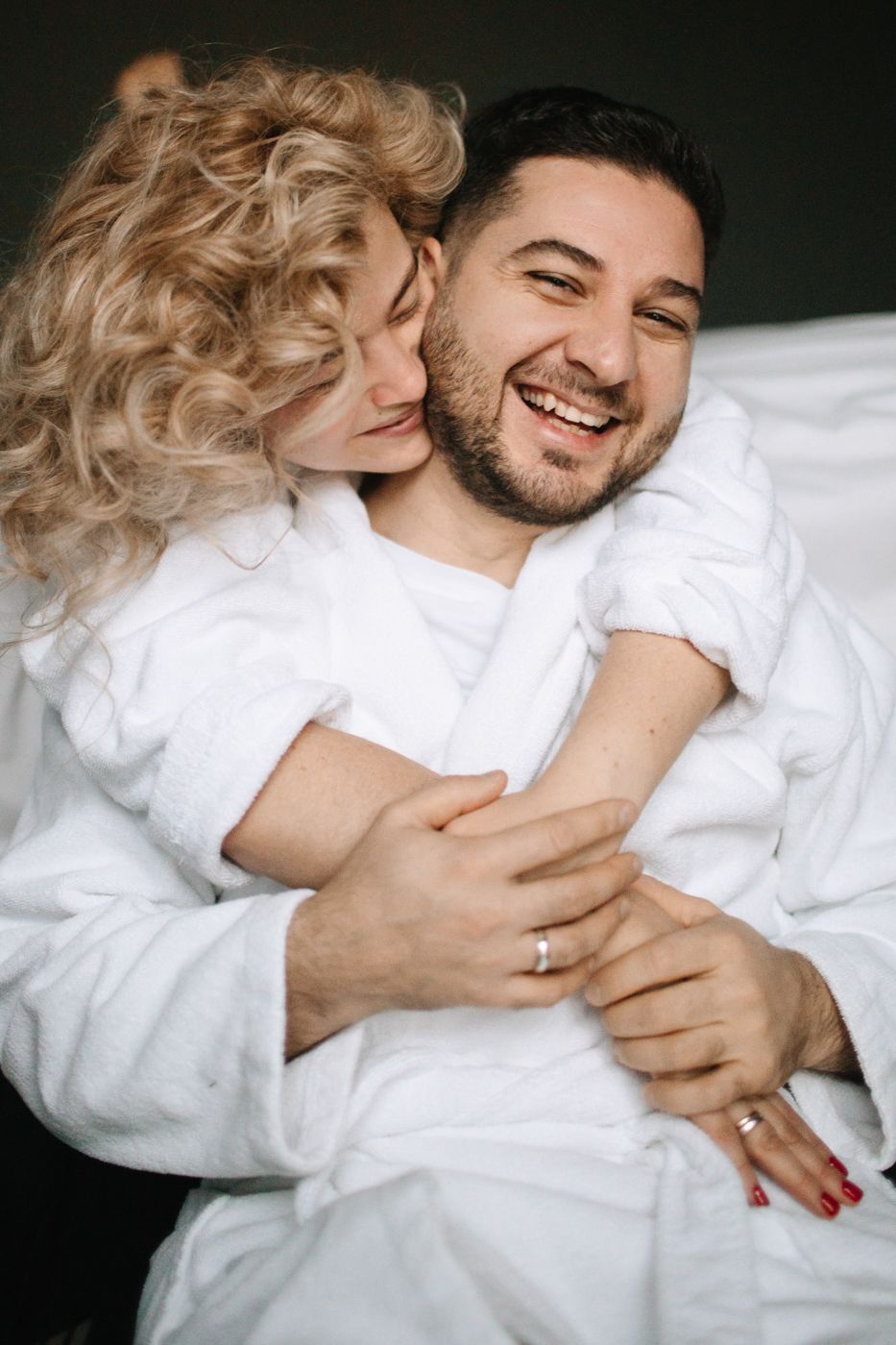 Intimate couple moment captured in white bedding.