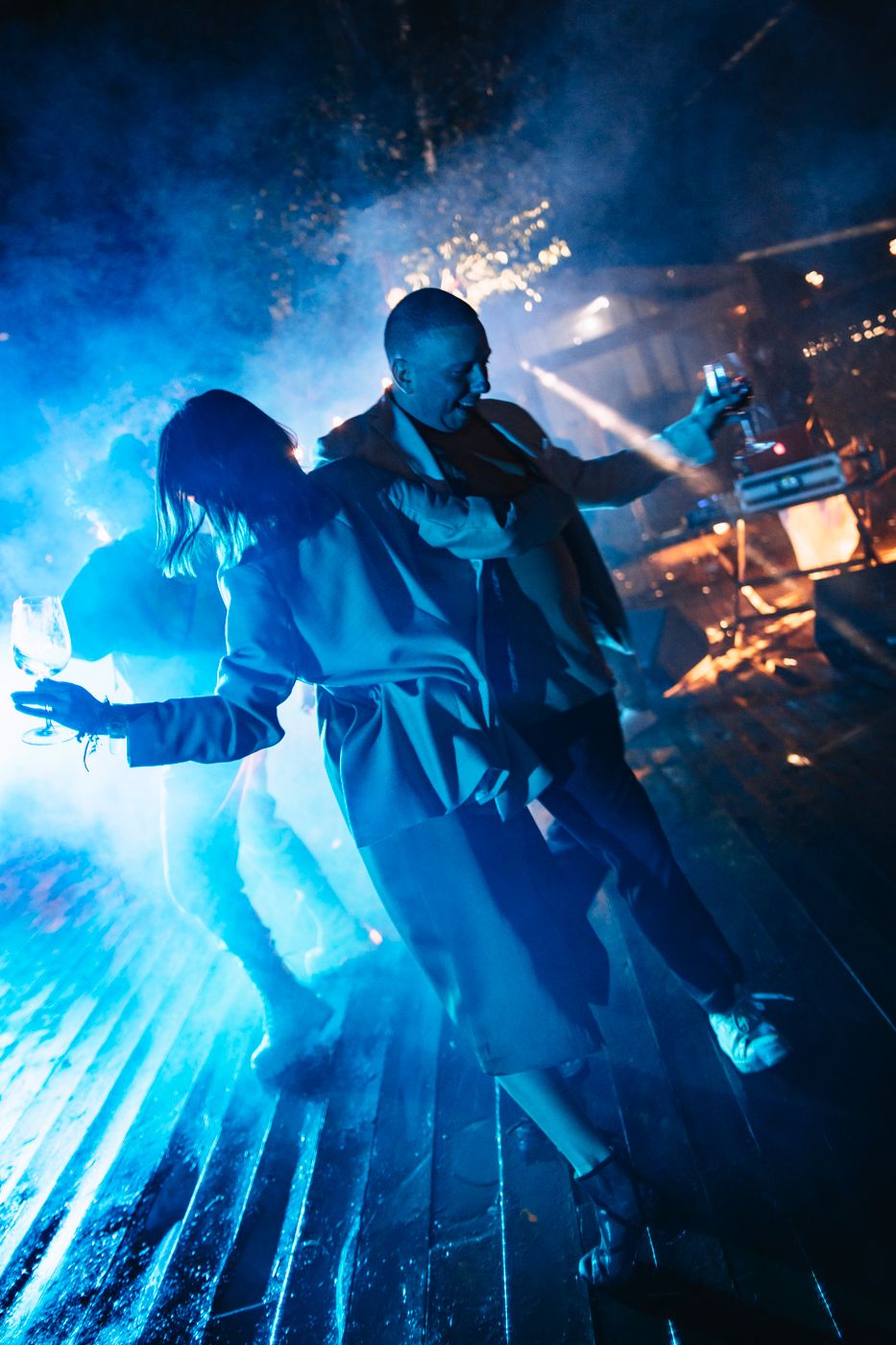 Performers on stage silhouetted against dramatic blue lighting and fog effects during an energetic concert performance.
