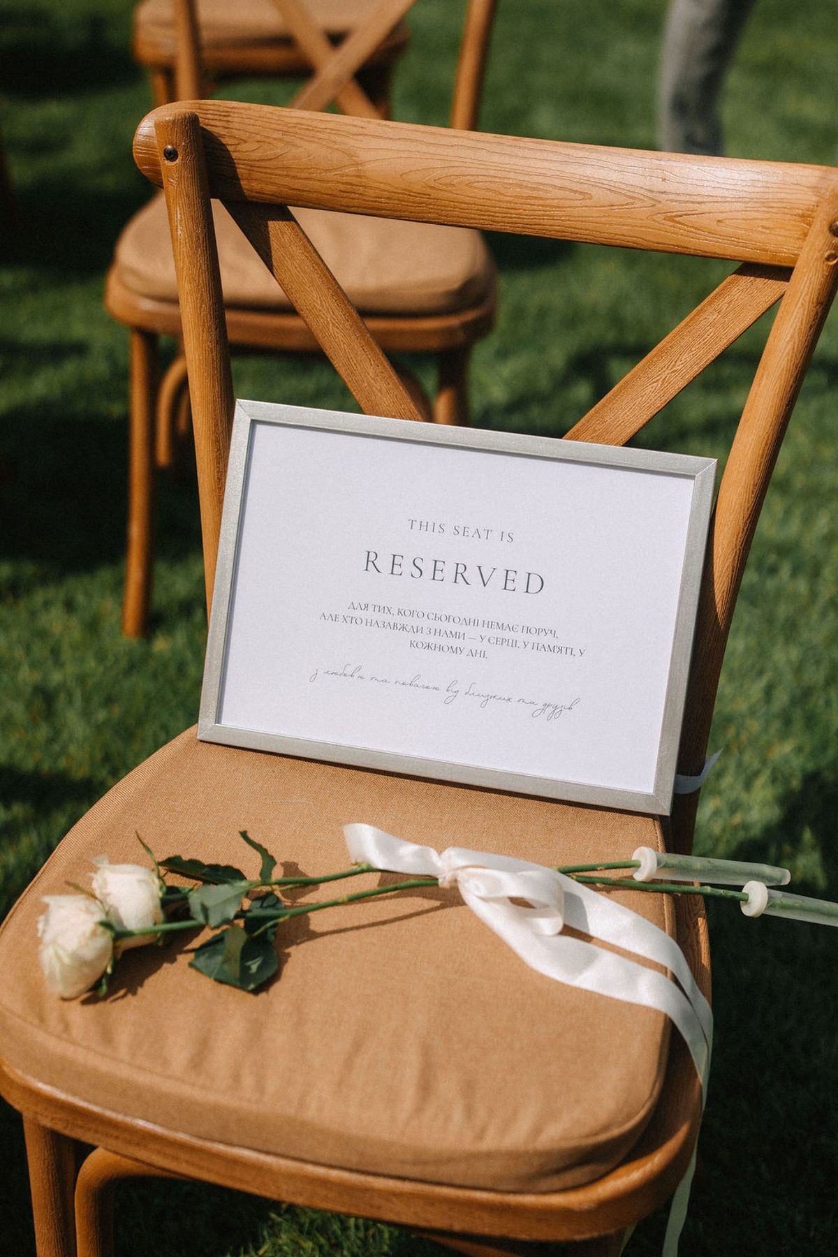 Wooden folding chairs with tan cushions and reserved signs displayed at an outdoor wedding ceremony on grass.