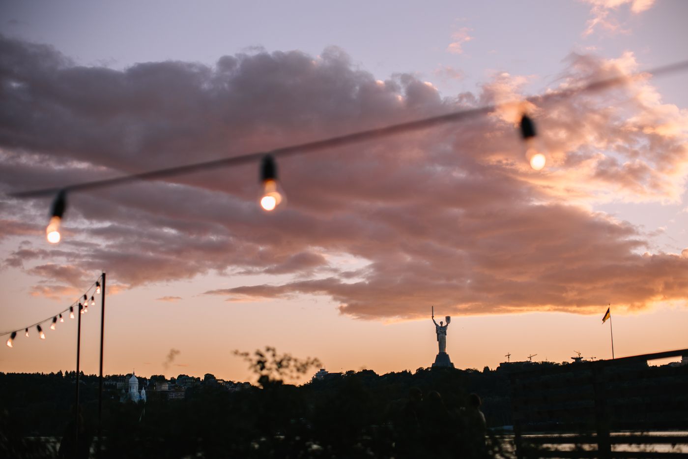 A dramatic sunset illuminates the sky with orange and pink clouds while silhouettes of power lines stretch across the horizon.