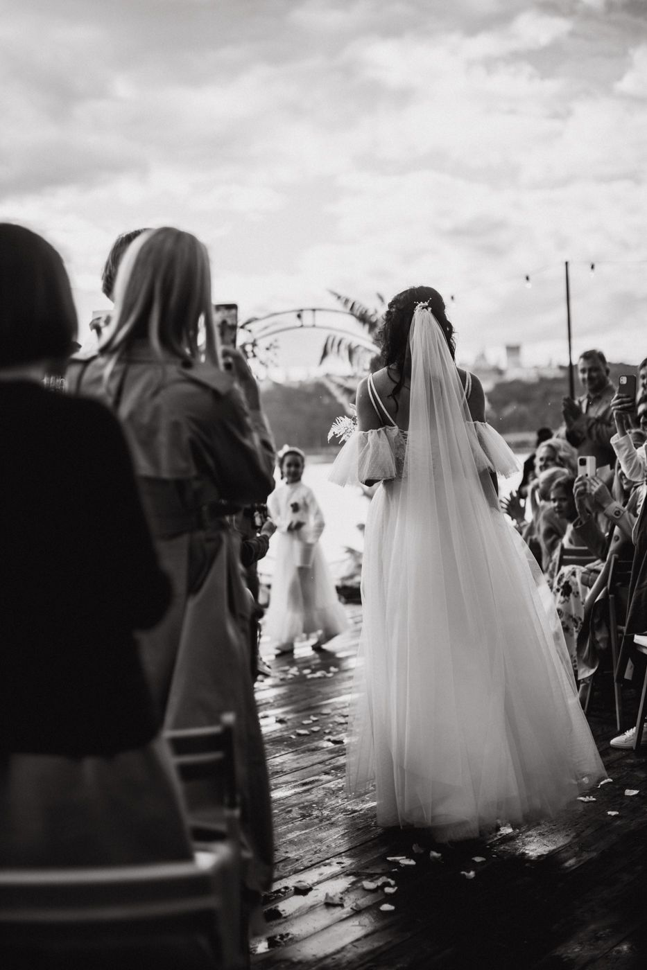 Black and white wedding photos showing brides in flowing white dresses walking outdoors under cloudy skies.