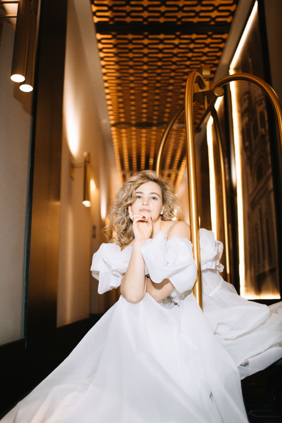 Fashion shots in modern hallway with geometric ceiling and gold lighting elements.