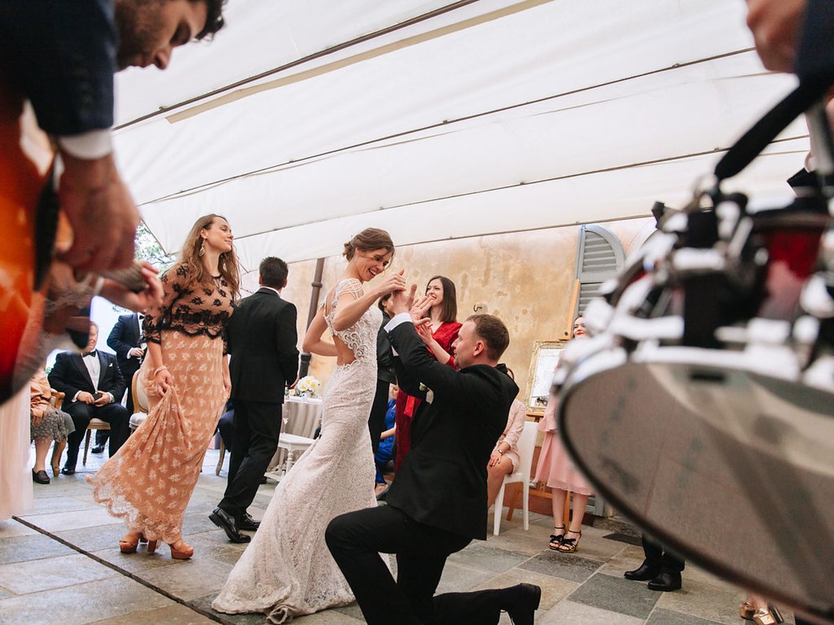 A couple shares their first dance as newlyweds while guests watch and capture the moment on a dance floor.