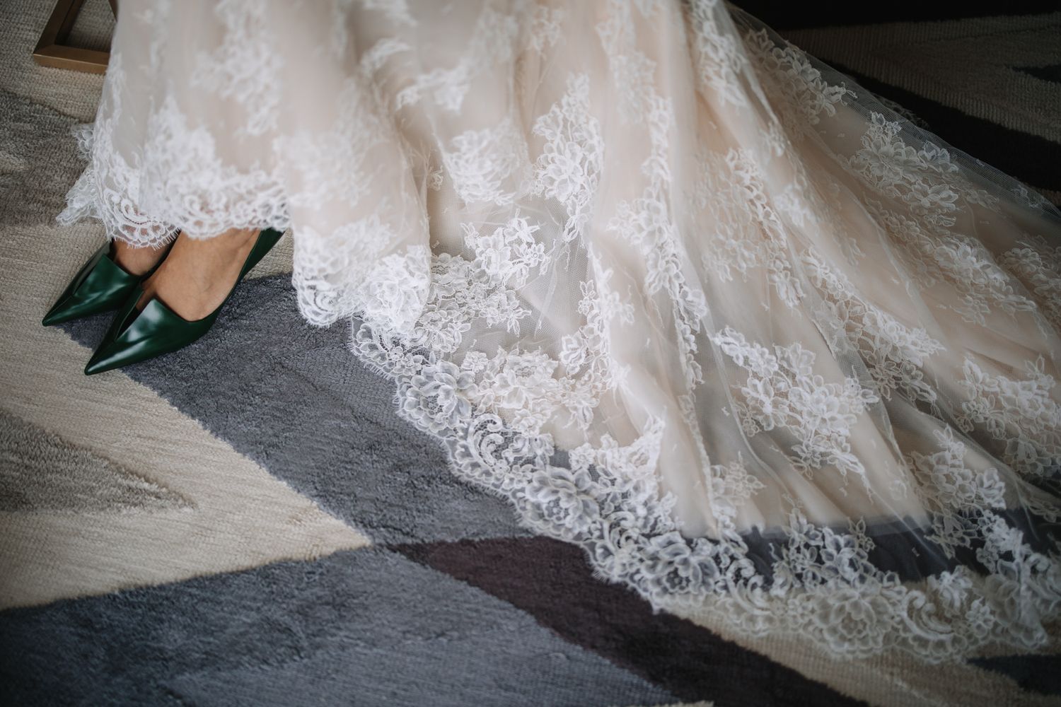 Close-up details of delicate lace trim and embroidery on a flowing white wedding dress train.