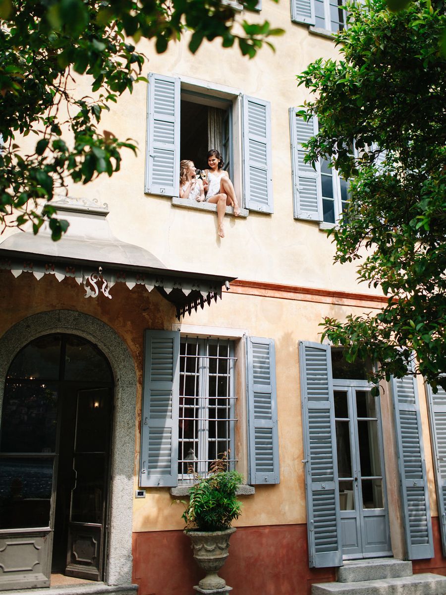 Historic French building exterior with blue shuttered windows and arched doorways in soft yellow and terracotta tones.