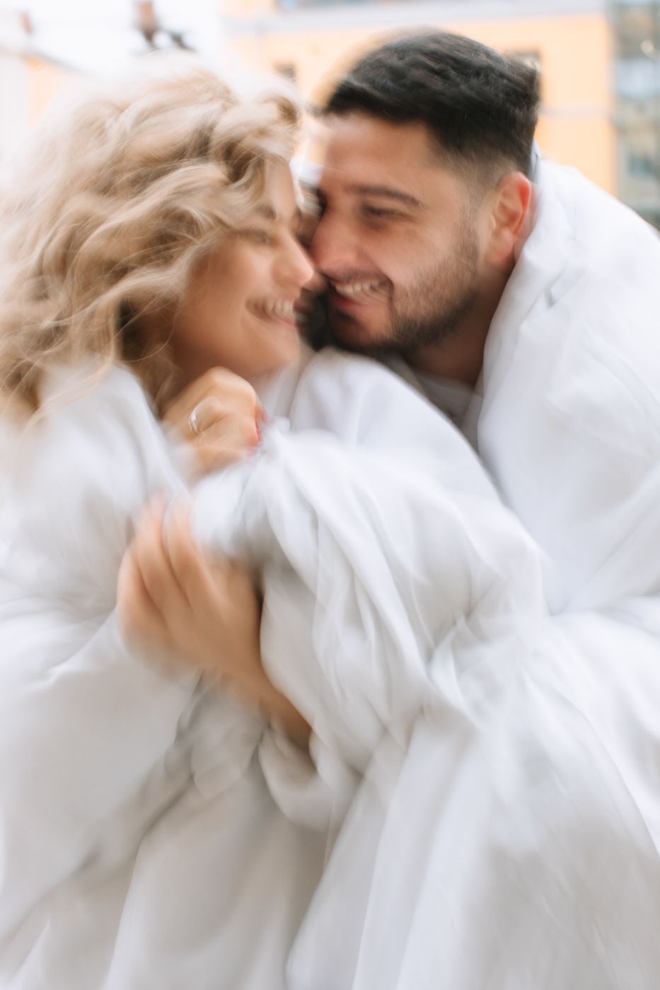 Intimate moment between couple in white robes sharing tender embrace with soft focus effect.