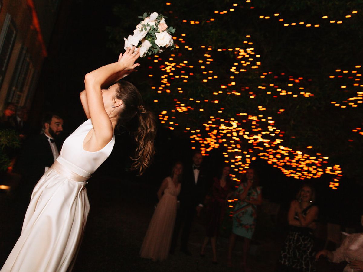 A couple dances gracefully under twinkling lights during a romantic wedding reception.