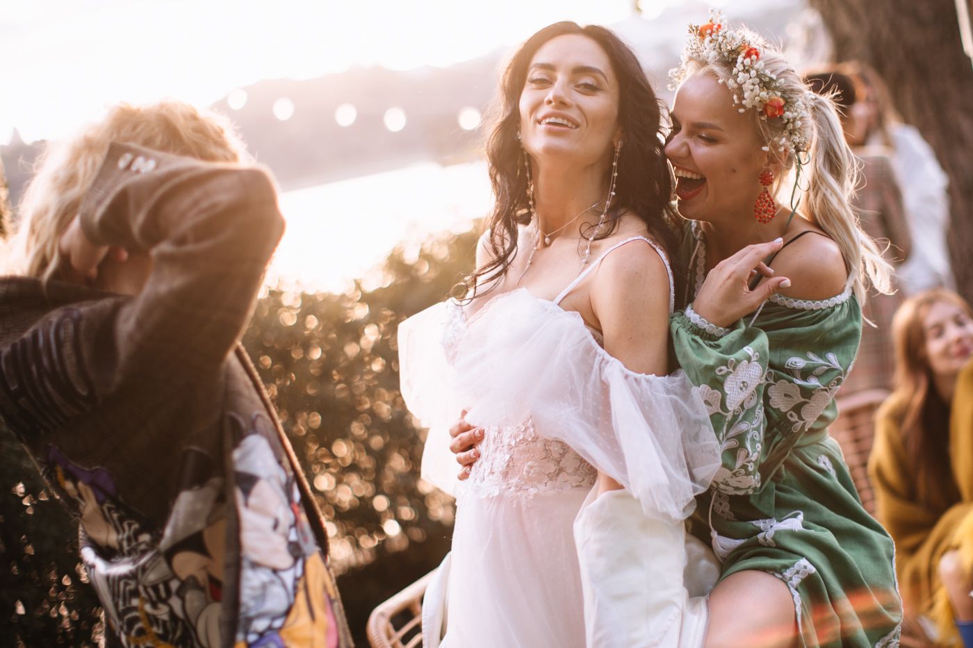 Wedding party celebrates outdoors with joyful dancing and laughter during golden hour festivities.