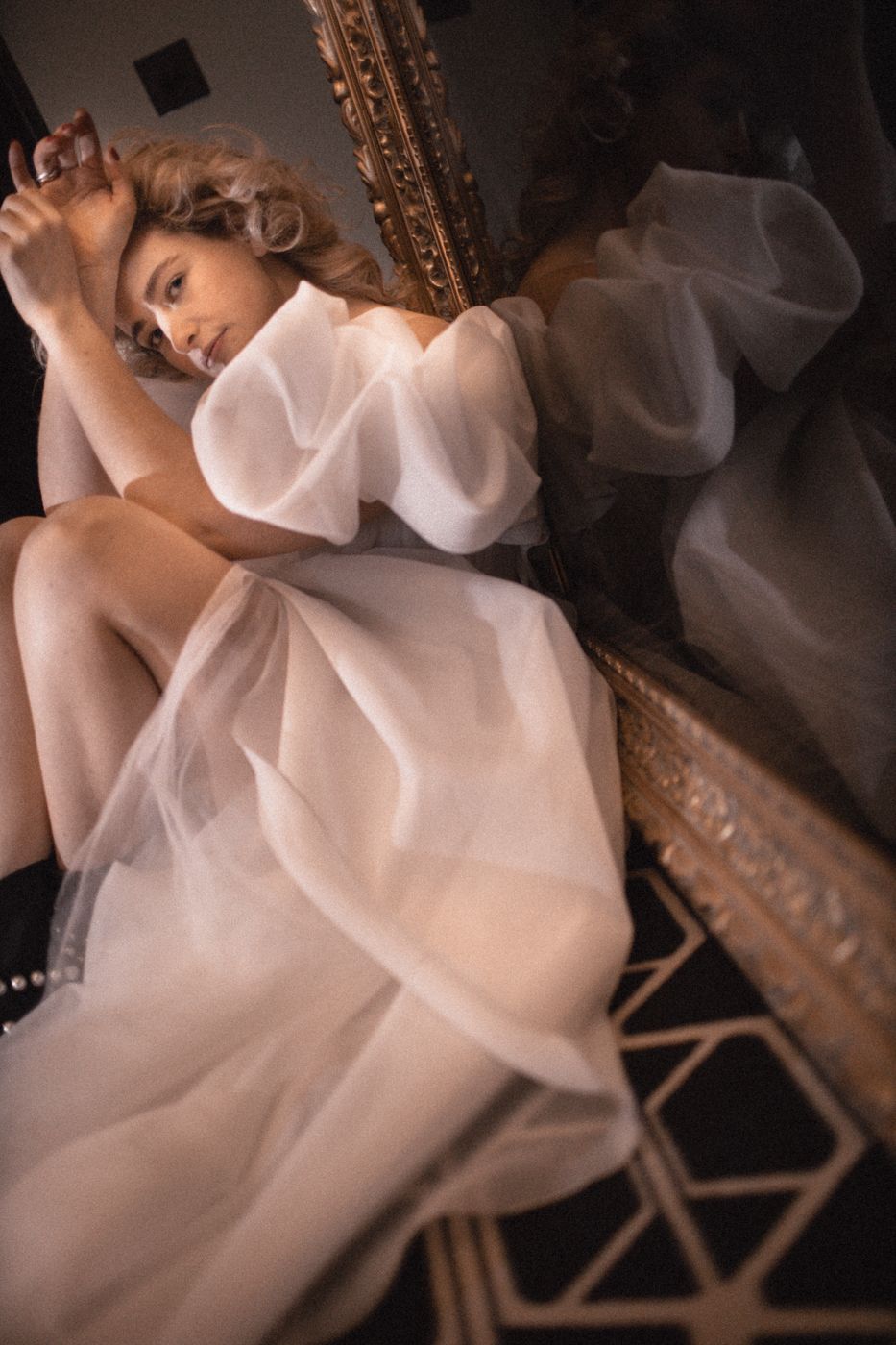 Ethereal bridal portraits reflected in ornate mirror with dramatic lighting.