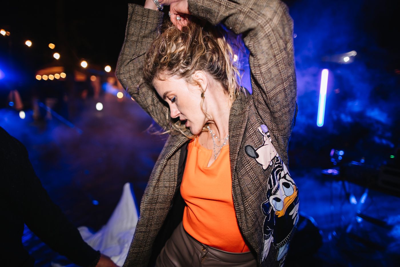 Performers in orange and dark outfits dance under dramatic blue stage lighting.