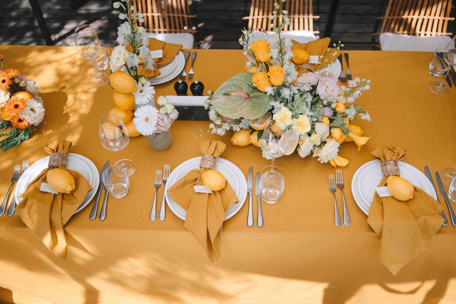 Elegant wedding reception table settings with gold chargers, white floral centerpieces and crystal glassware in warm lighting.
