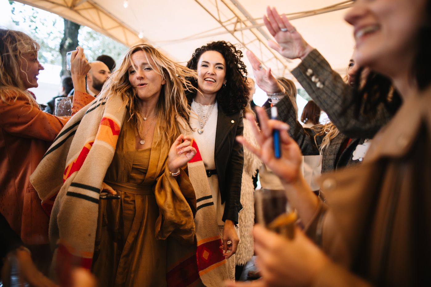 Group of people dancing and celebrating at a lively indoor party with warm lighting and joyful expressions.
