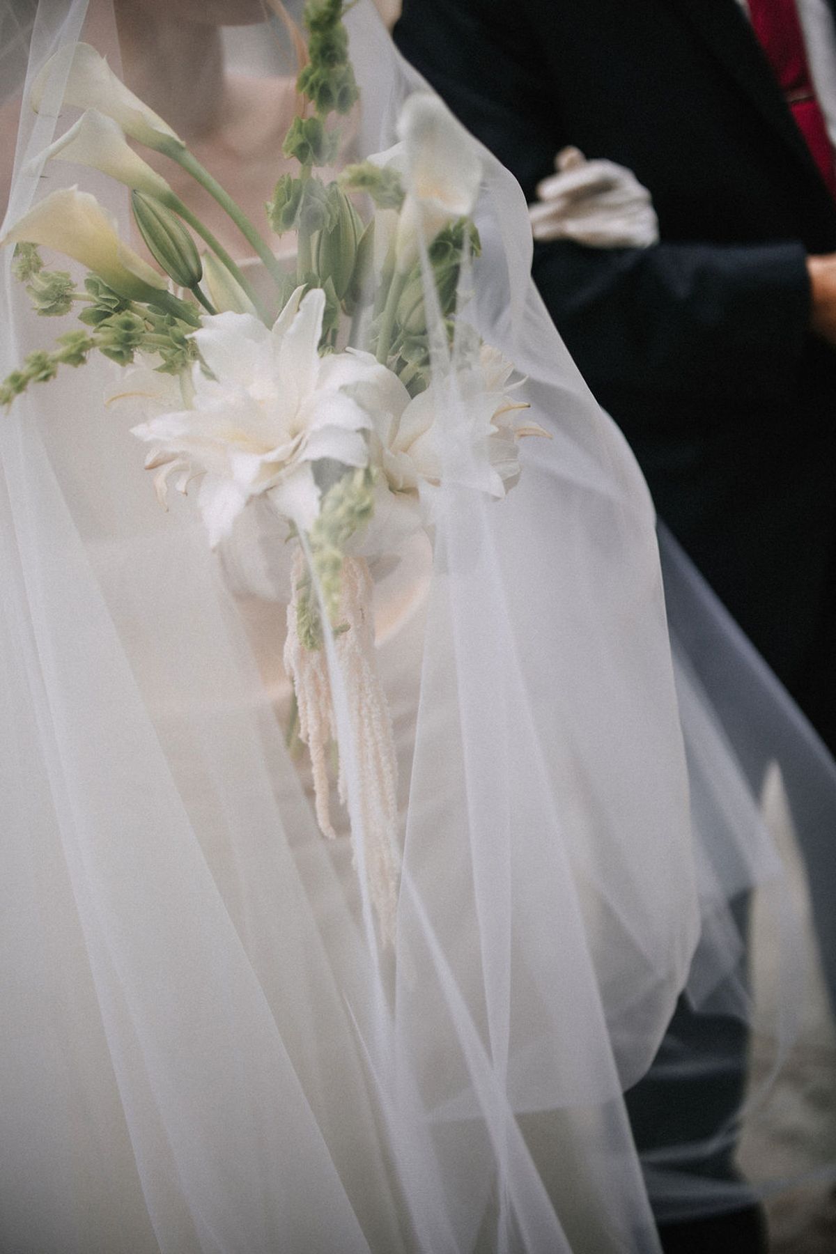 White tulle fabric decorations with delicate greenery line church pews for an elegant wedding ceremony.
