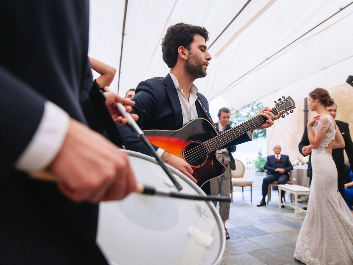 A live band plays instruments during a wedding reception with a guitarist in focus.