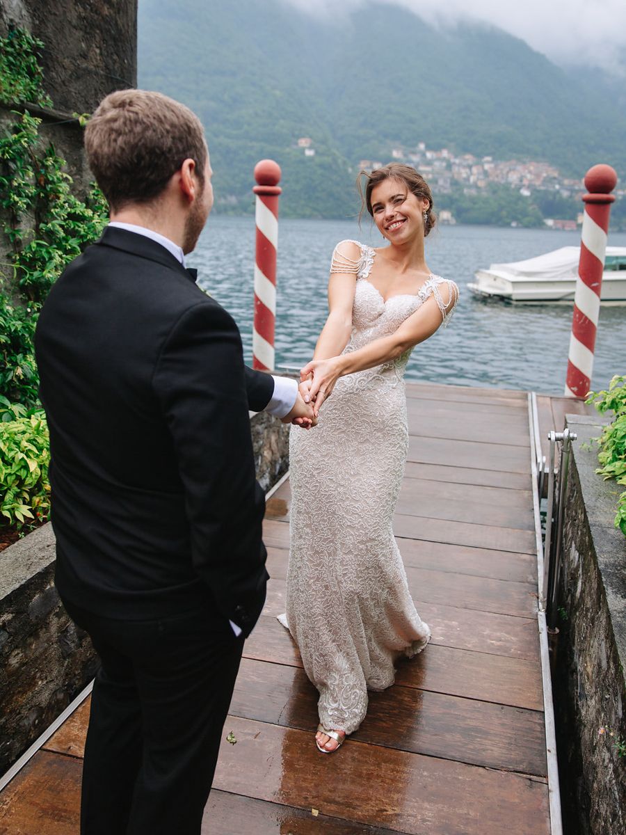A couple shares a romantic moment on a wooden dock overlooking a misty lake surrounded by mountains.