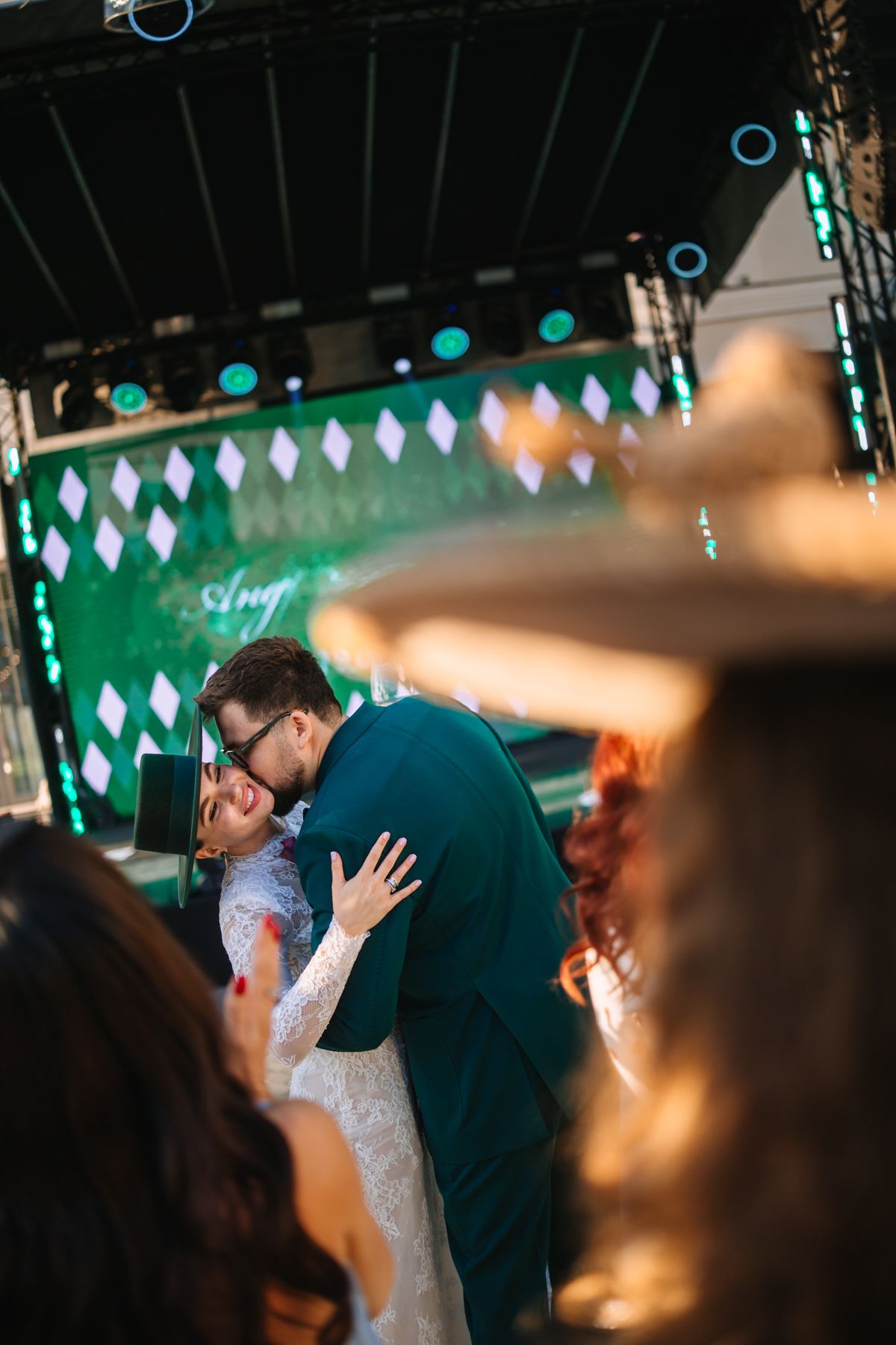 A couple shares an intimate dance together at a wedding reception with teal lighting and diamond decor in the background.