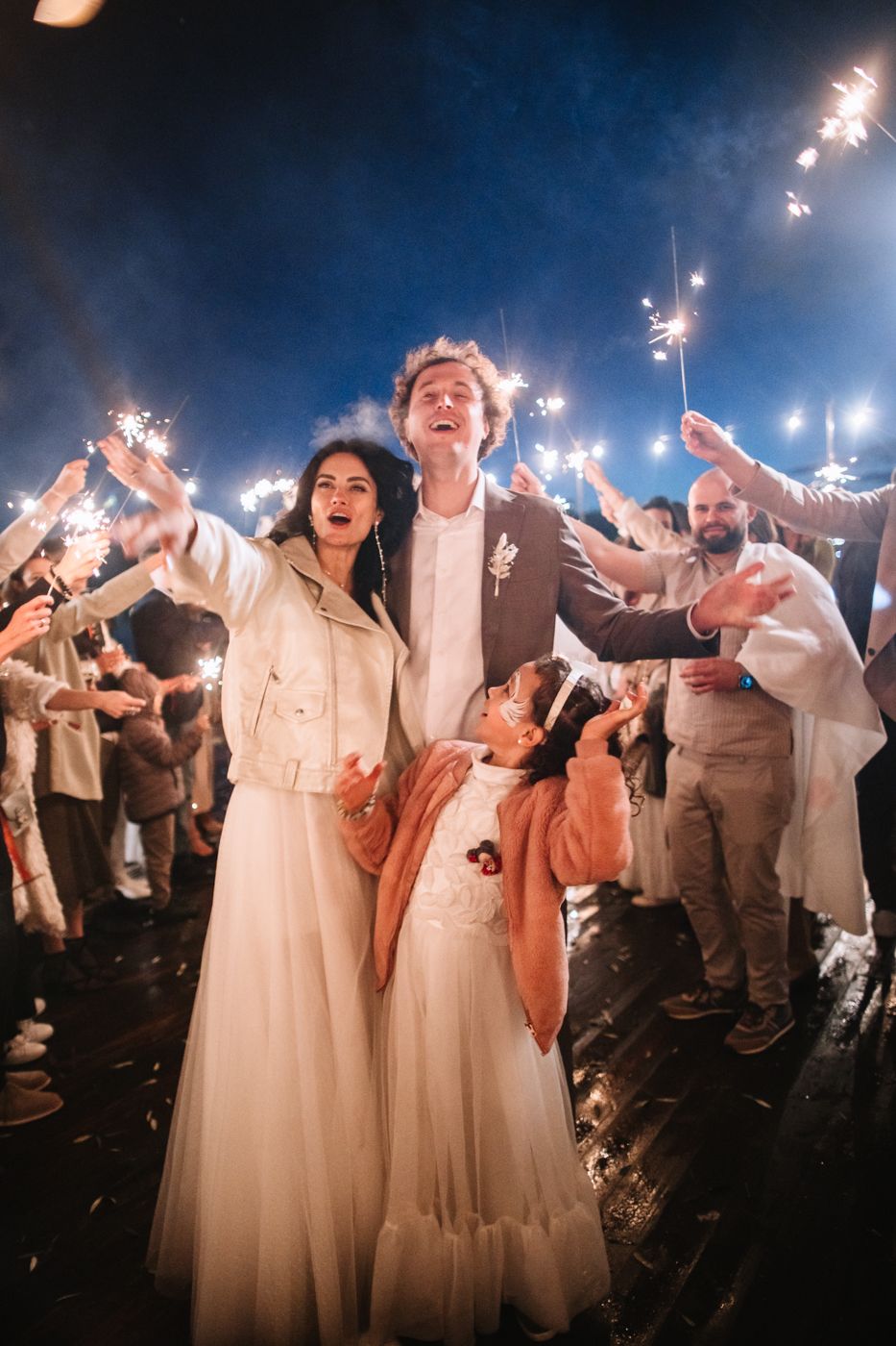 Wedding celebration at night with sparklers creating a magical atmosphere as guests and wedding party celebrate together.
