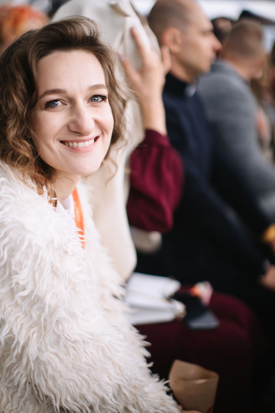 A series of four candid shots showing someone in a white fluffy sweater sitting in an audience at an event.