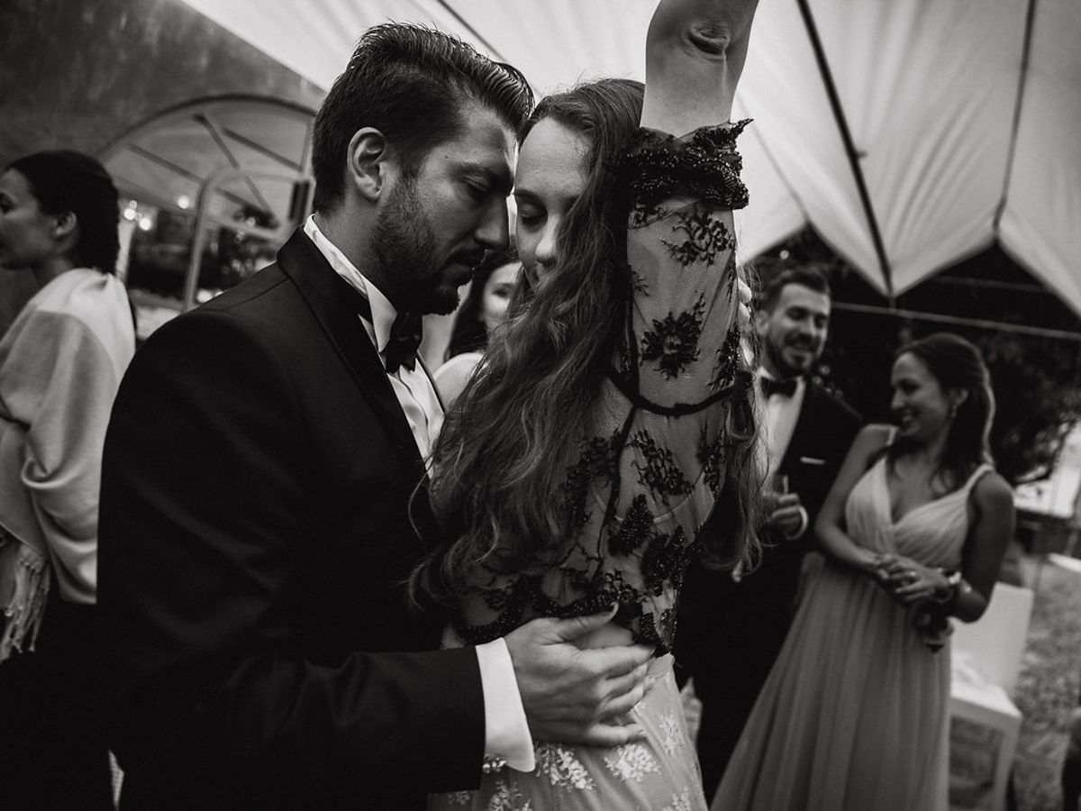 Musicians perform live at an outdoor wedding reception under a white tent with guests enjoying the celebration.