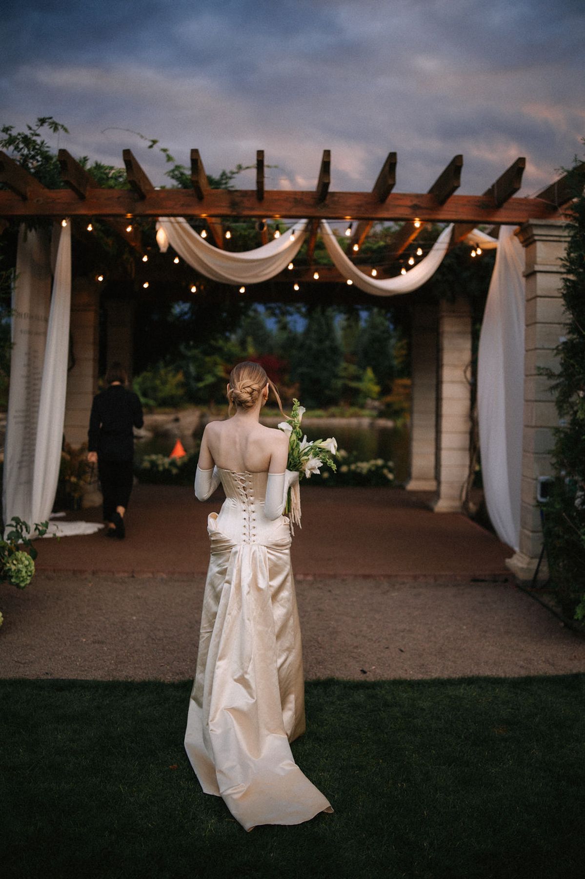 A sequence of outdoor wedding venue photos showing a white gown against a dusky evening backdrop with draped fabric decor.