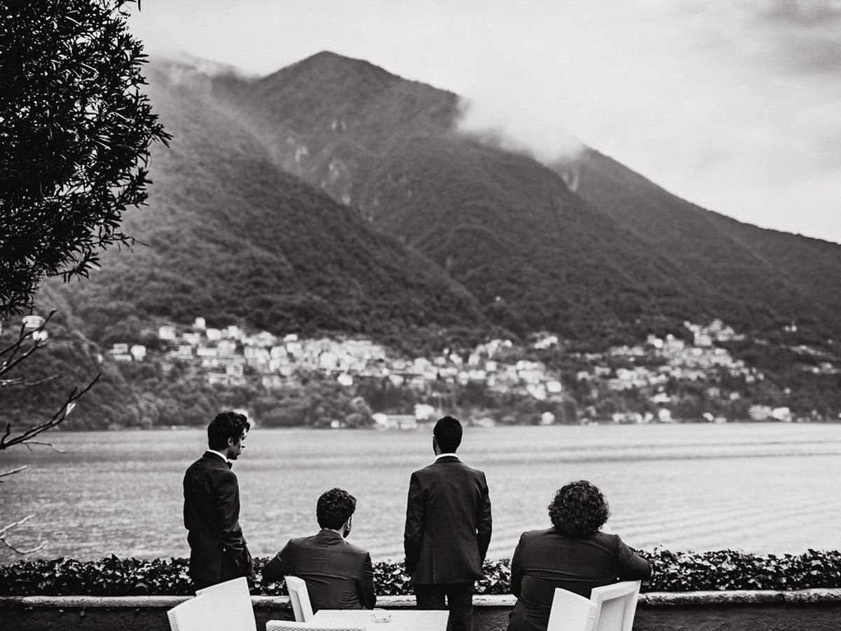 Four people sit in chairs overlooking a scenic mountain lake view in black and white.