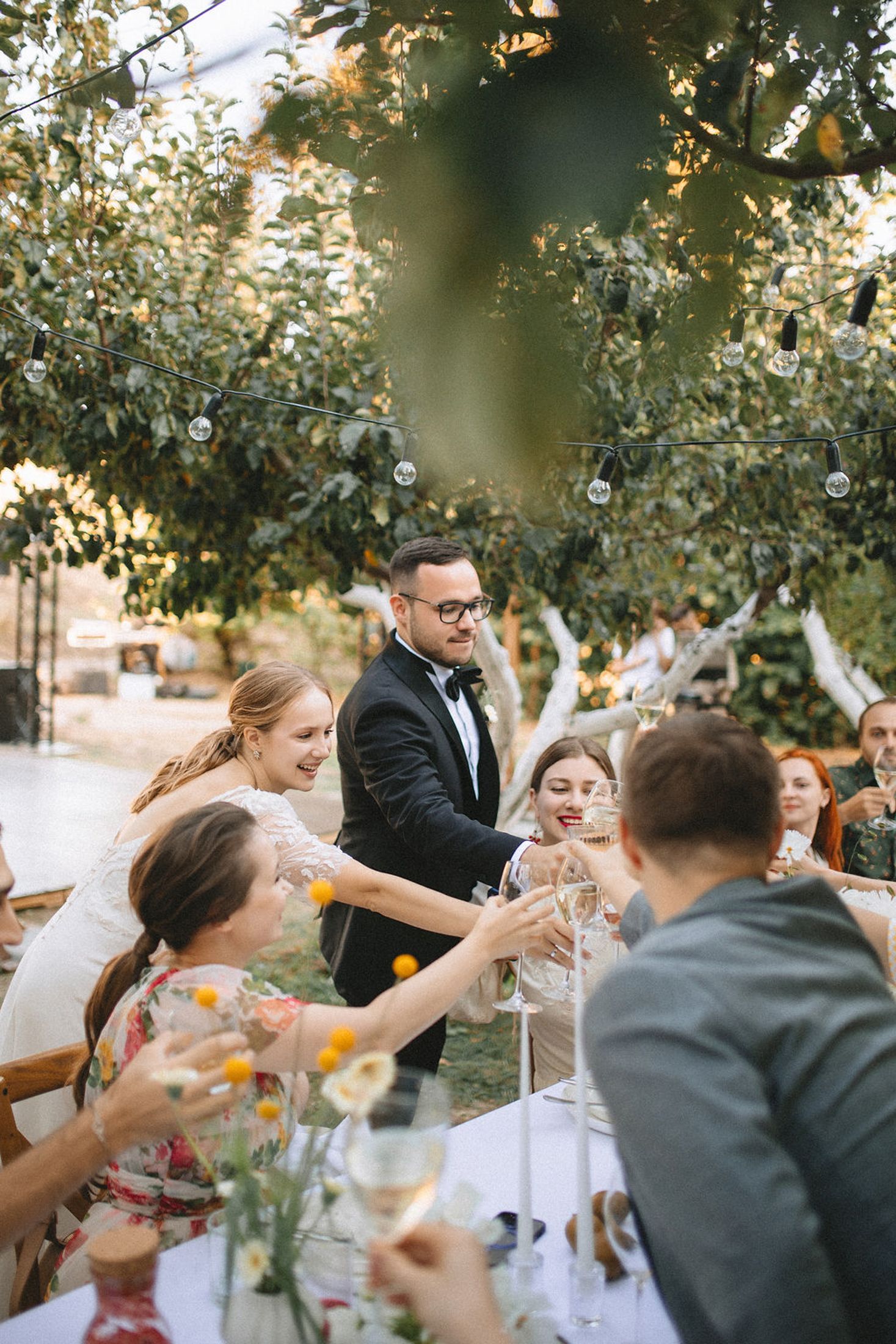 Guests raise their glasses in a toast during an elegant outdoor garden reception celebration.