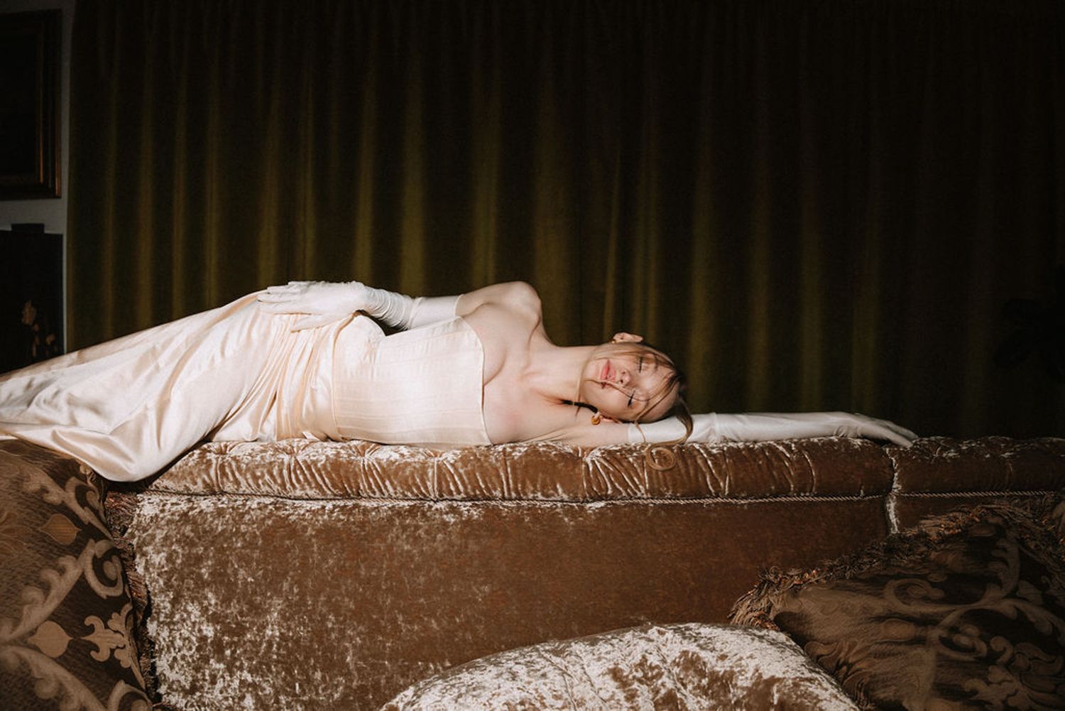 A sleeping figure lies peacefully on a dark textured surface in dim lighting.
