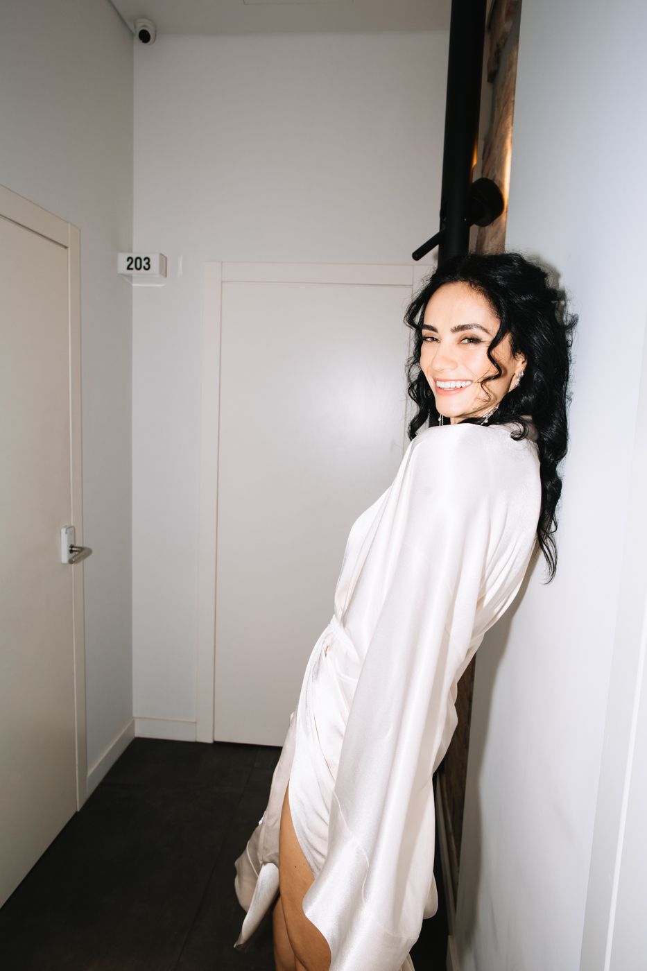 A series of playful poses in a white hallway with natural lighting and minimalist aesthetic.