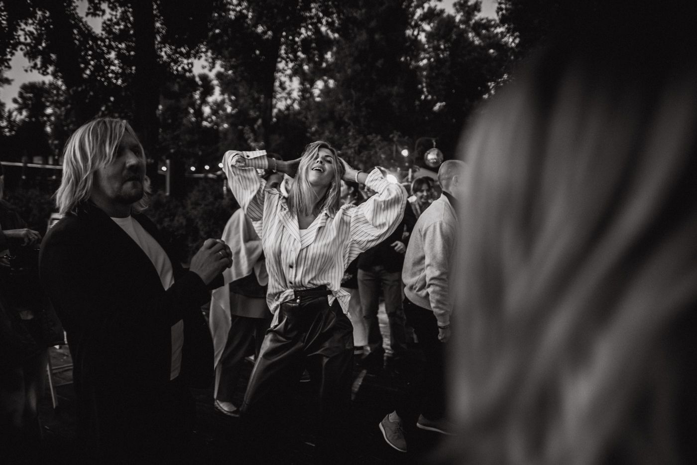 Black and white photo of people dancing and celebrating at an outdoor party or gathering.
