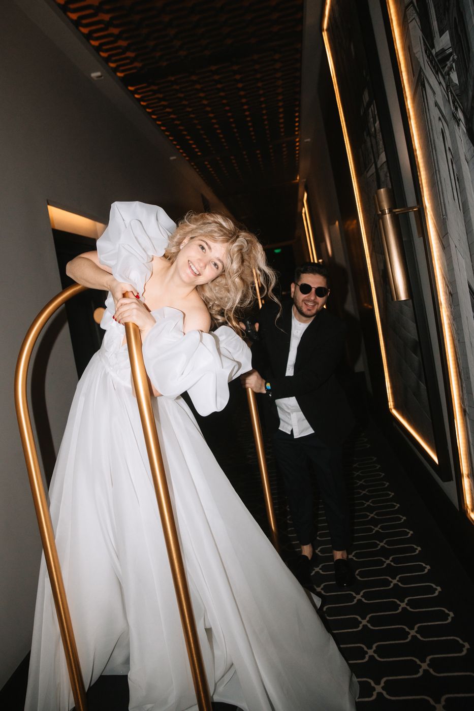 Dynamic shots of flowing white gown moving through hallway with gold accents.