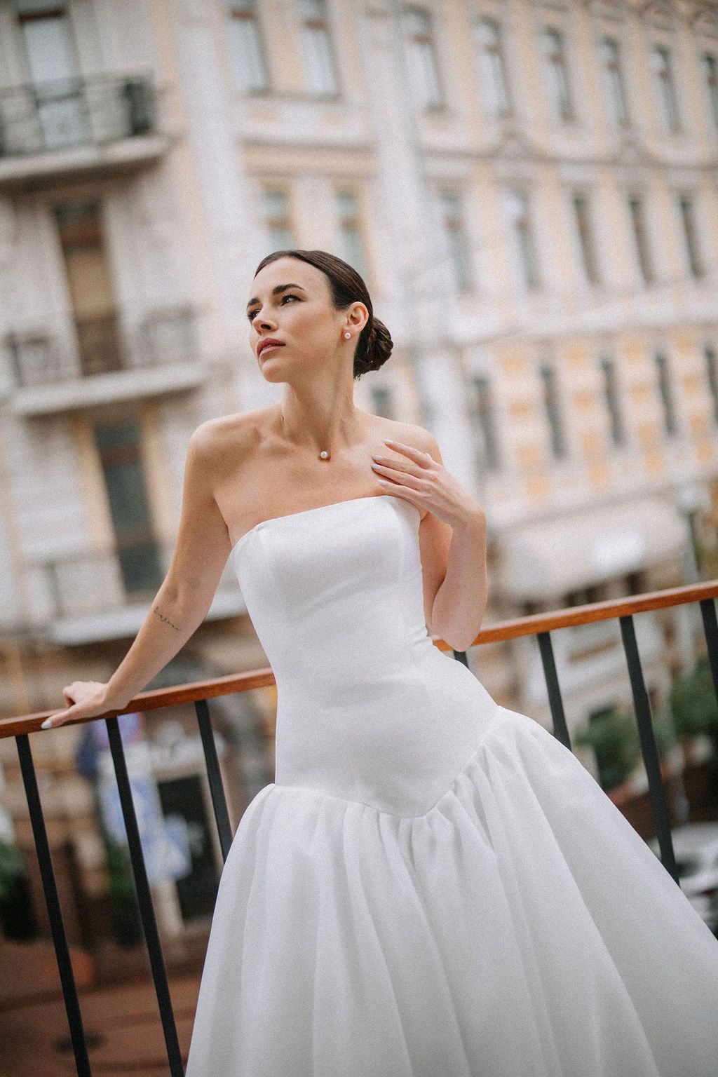 Elegant bride in white ballgown poses gracefully against an ornate building exterior with balconies.