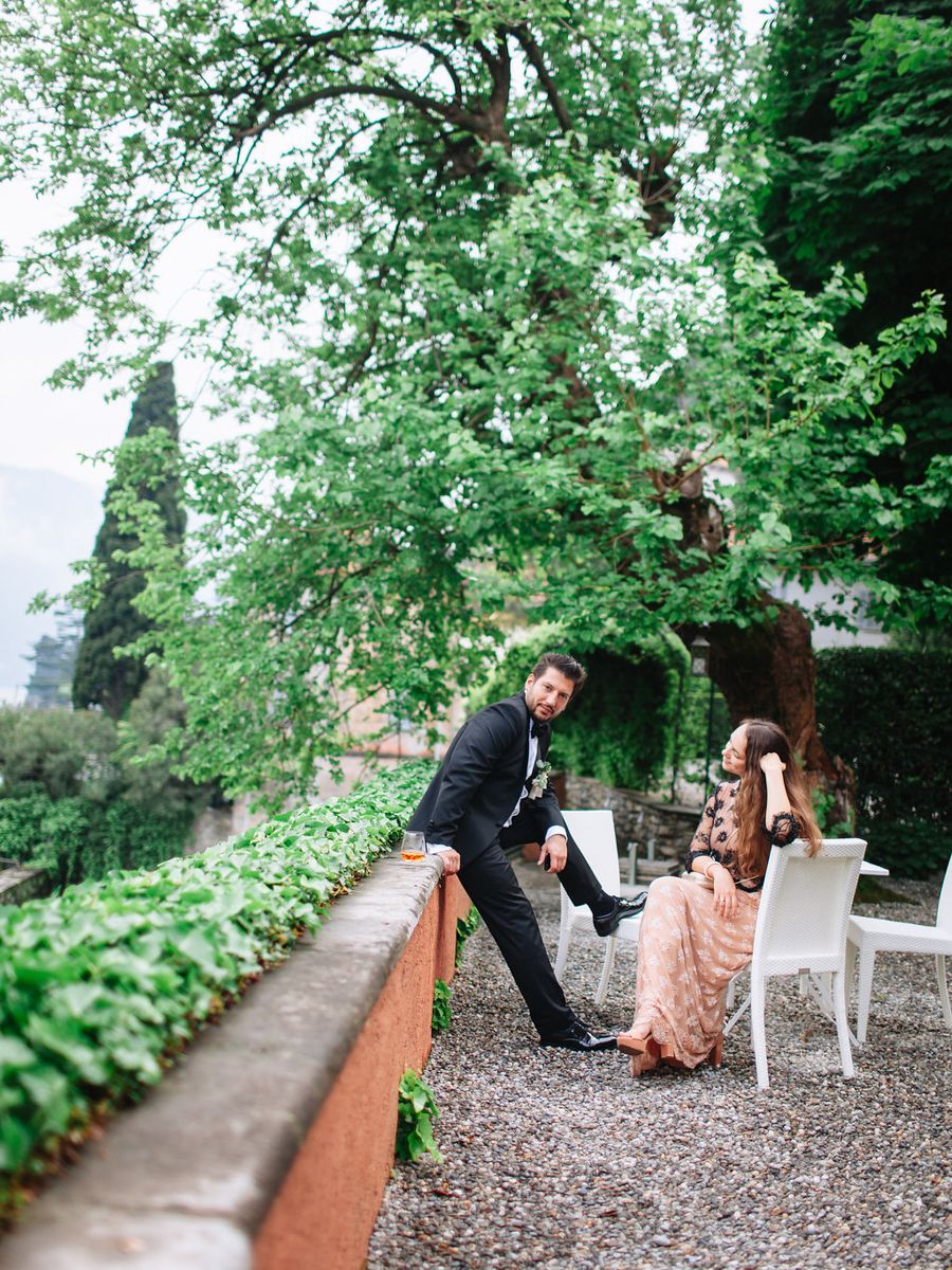 Playful couple having fun on a rustic garden path surrounded by lush green foliage and trees.