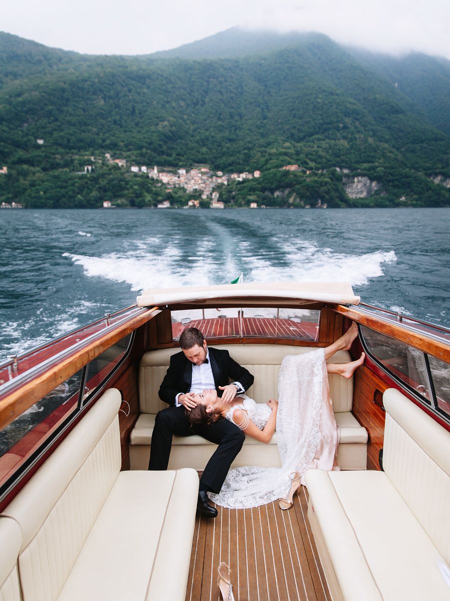 Couple relaxing on a luxurious wooden boat deck with scenic mountain views on Lake Como.