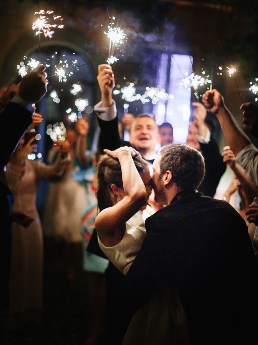 Sparklers illuminate a dark reception as party guests celebrate during a festive nighttime gathering.