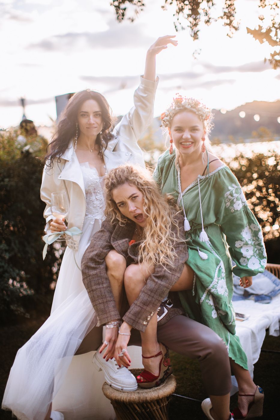 Friends laughing and enjoying a candid moment together outdoors at sunset with string lights in the background.