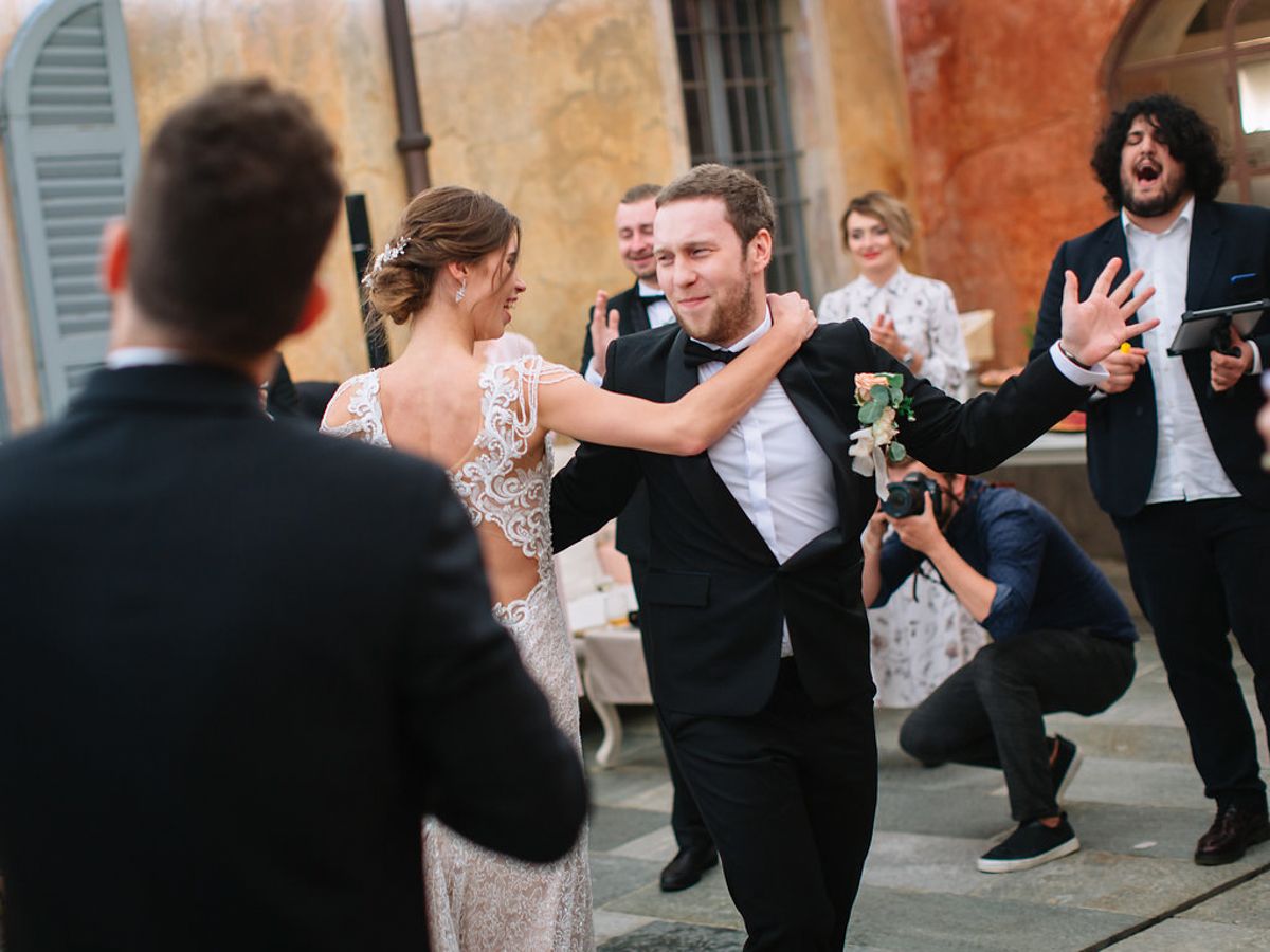People dancing together in a social dance class or workshop with a warm yellow wall in the background.