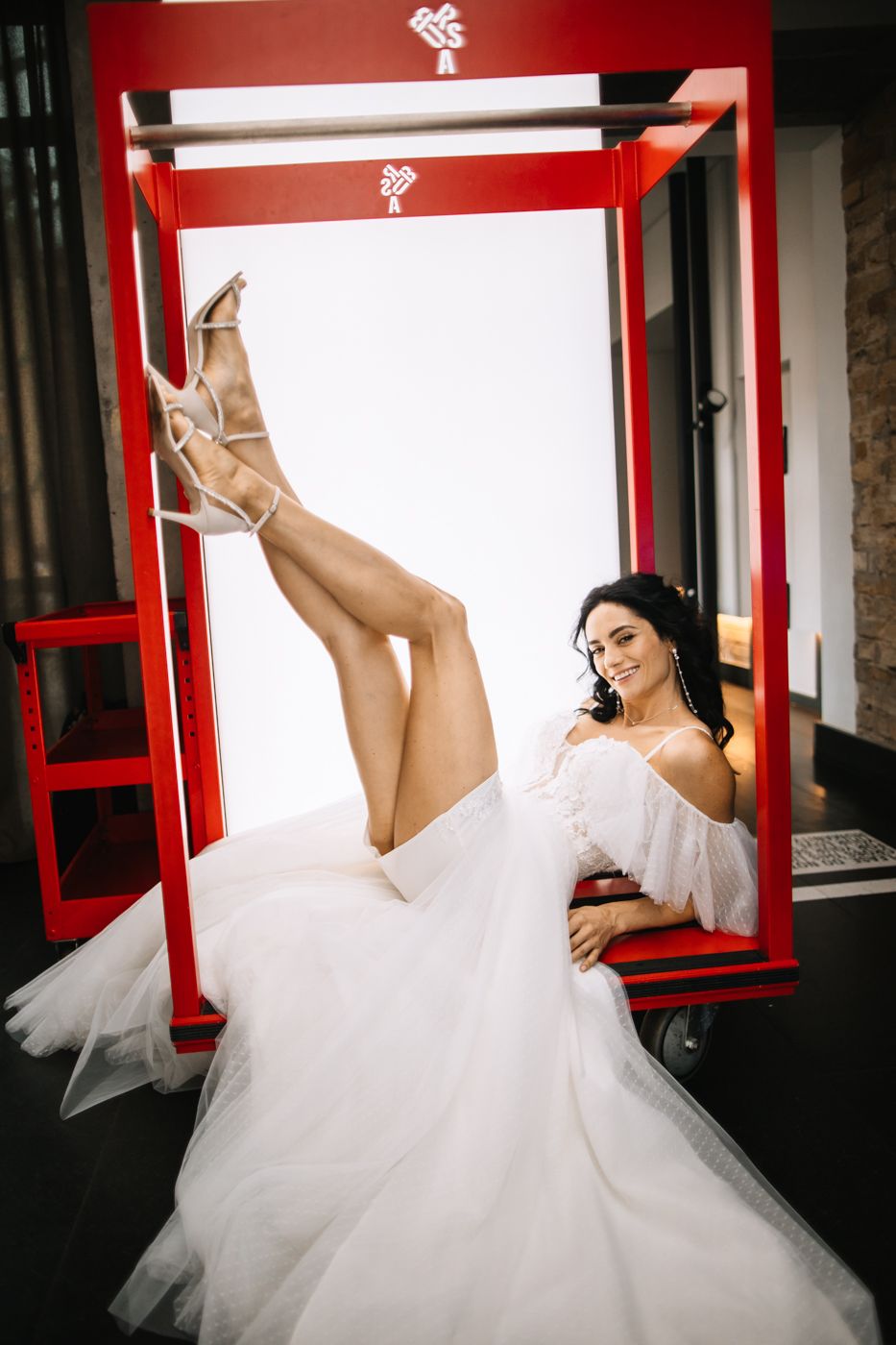 A series of artistic wedding photos showing a bride in a white tulle gown posing playfully against red window frames.