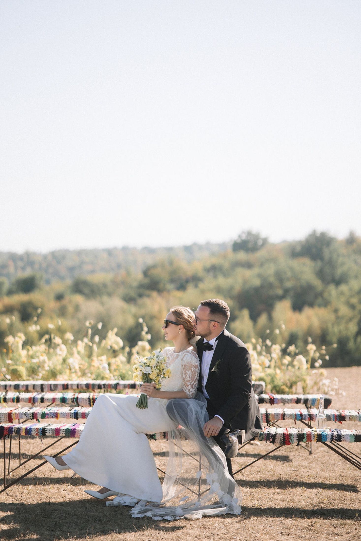 Couple sitting on rustic wooden swing in vineyard during golden sunset.
