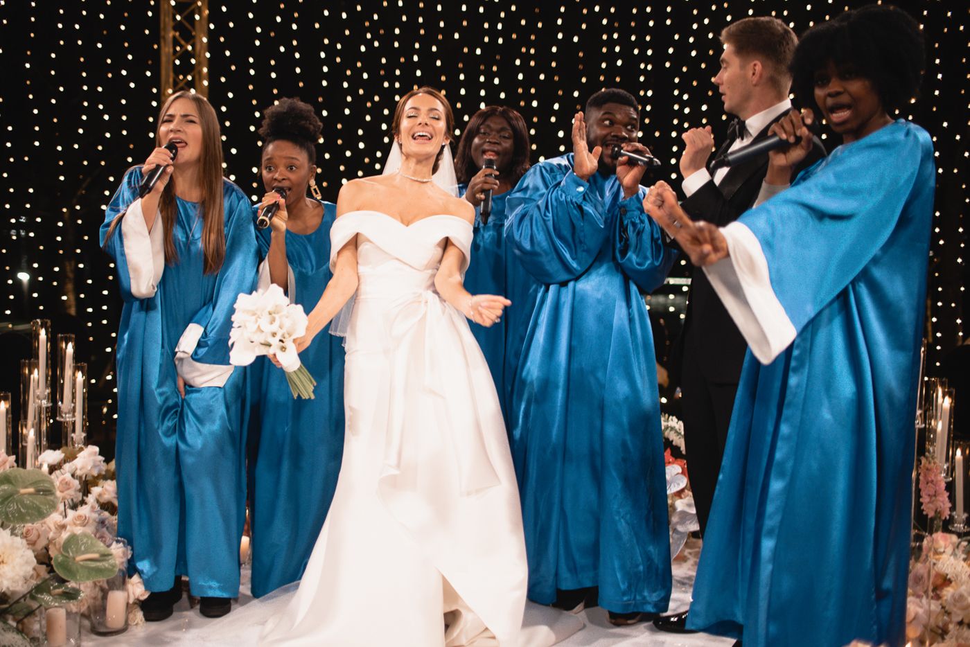 Wedding party wearing bright blue robes celebrates during an outdoor ceremony.