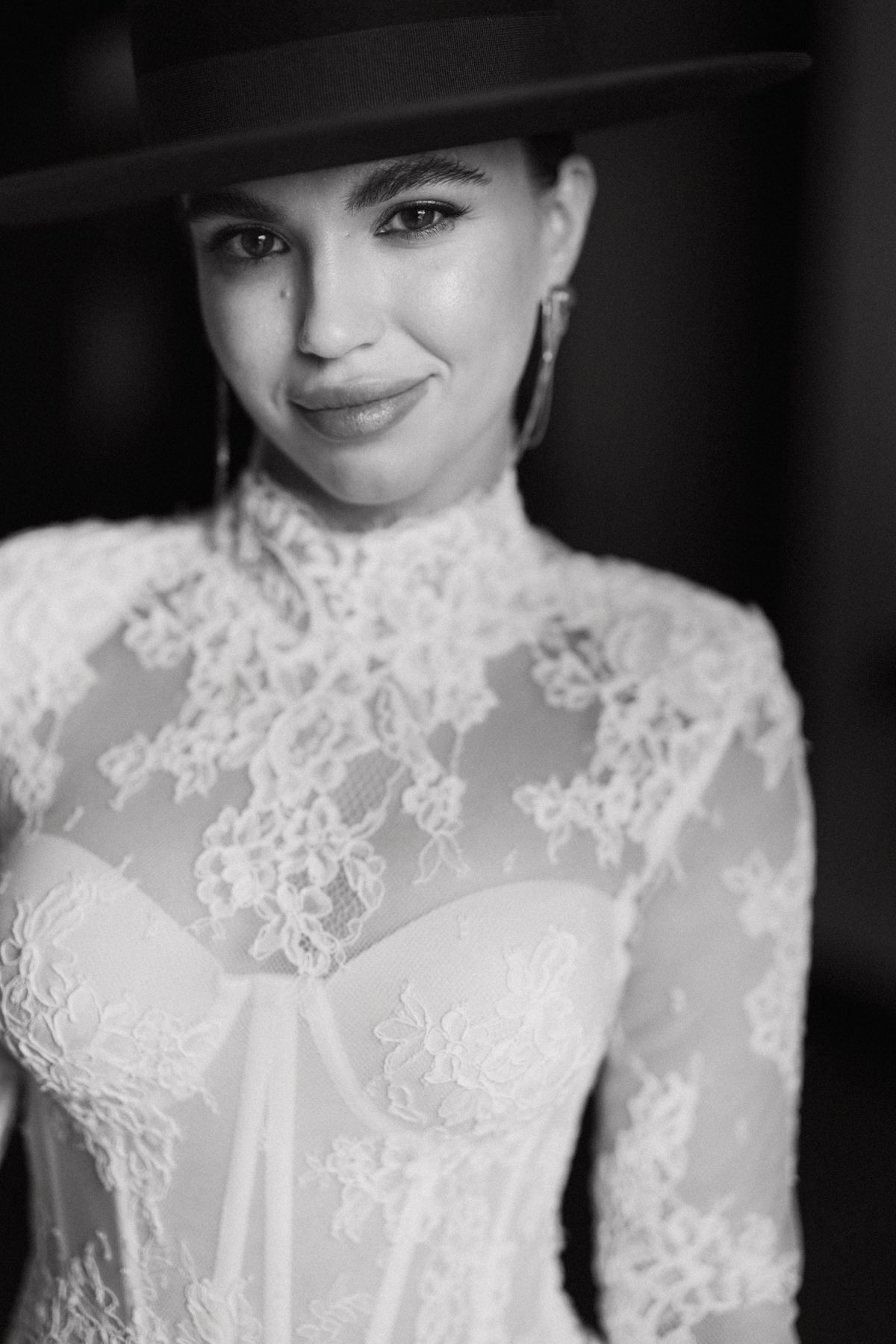 A black and white portrait showcasing delicate lace details on a high-necked wedding dress bodice.